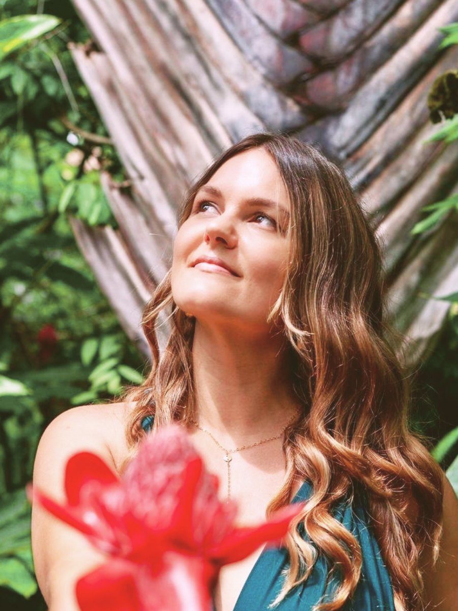 Selina looking up toward the light beside a red ginger flower