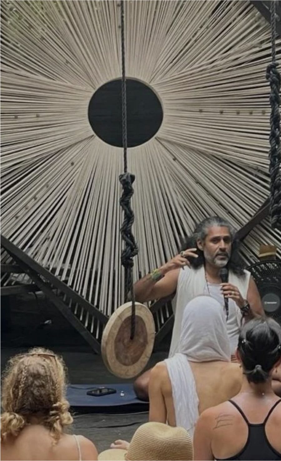 Aly Khan speaking to a circle beneath a woven sunburst