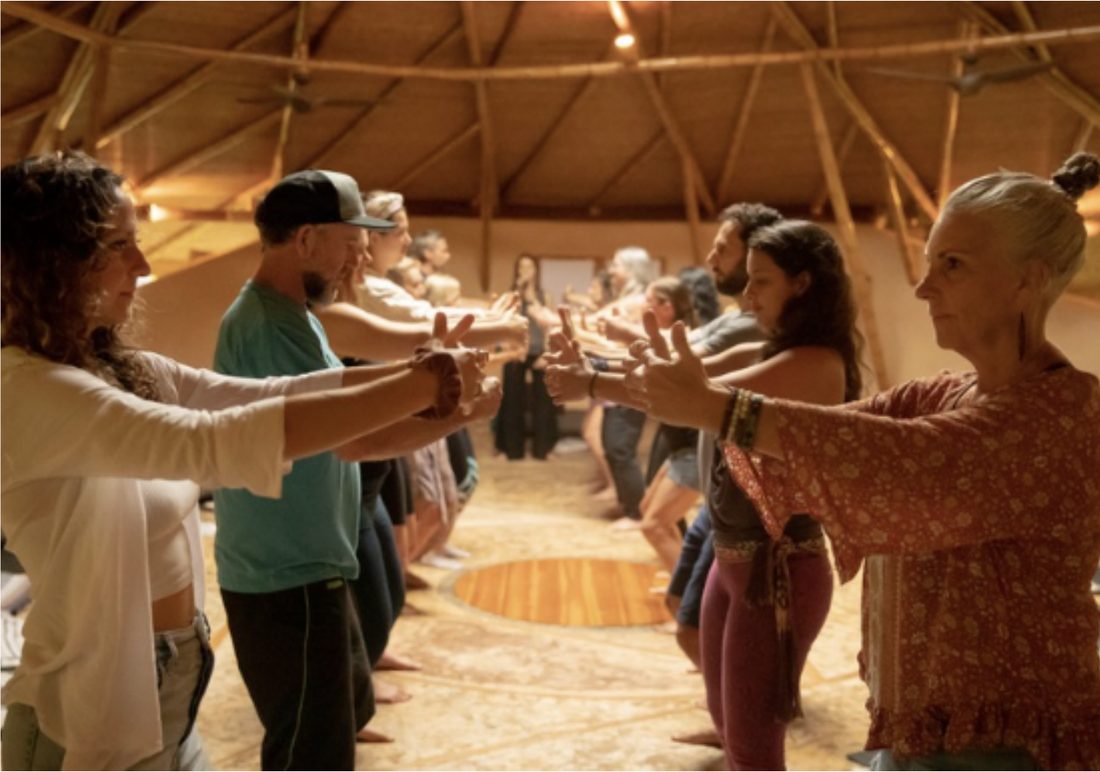 Participants facing each other with joined hands in a ceremony space